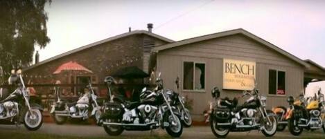 A row of motorcycles parked in front of a building with a sign that reads "BENCH."