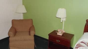 Una habitación con un sillón a rayas, una mesita de noche con lámpara y un teléfono.