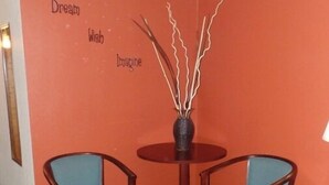 Una habitación con dos sillas azules alrededor de una pequeña mesa de madera con un florero.