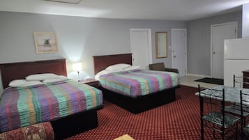 Habitación de hotel con dos camas, un escritorio, una silla, un refrigerador y un televisor.