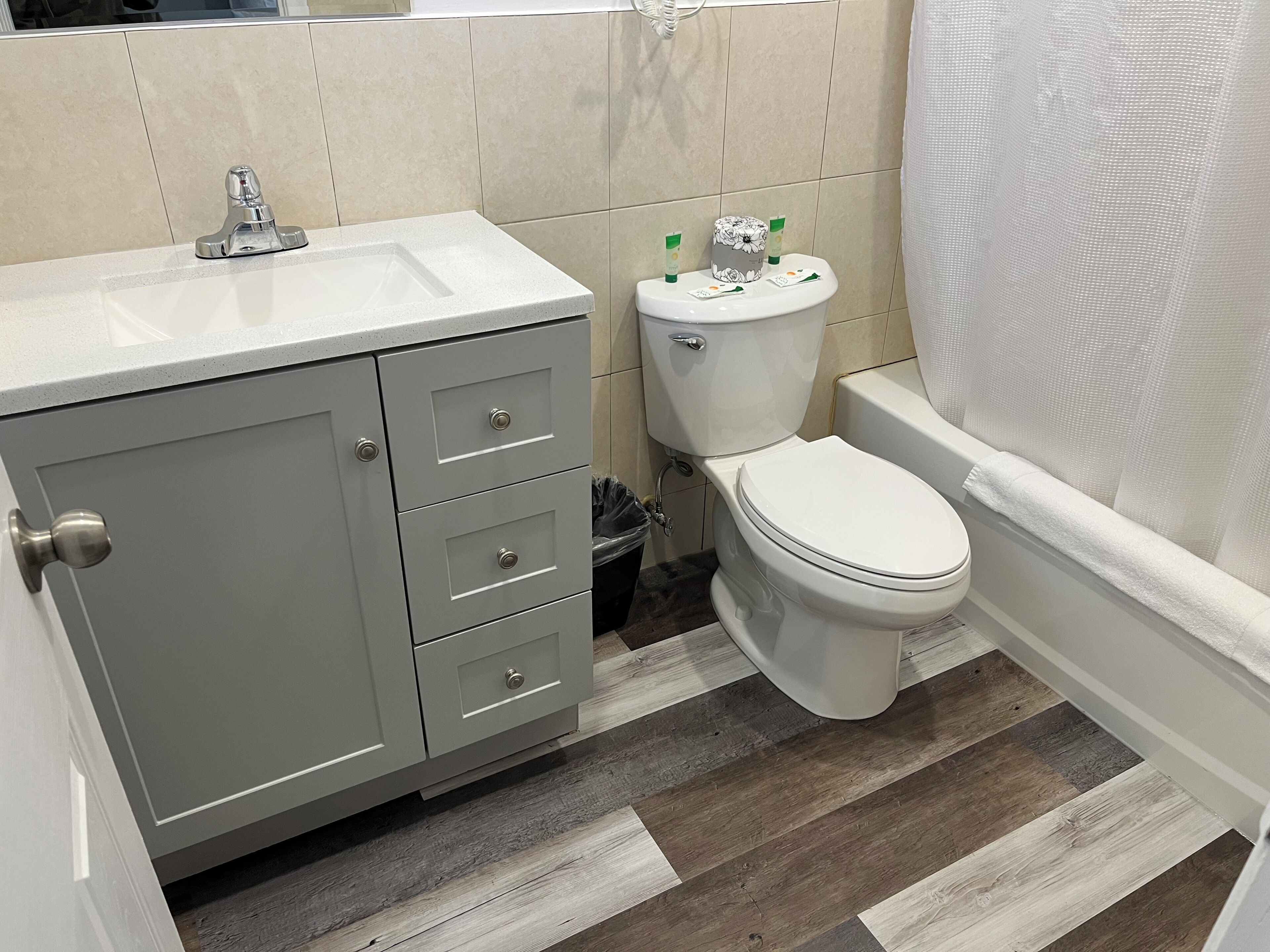 A bathroom with a toilet, sink, cabinet, and shower curtain.