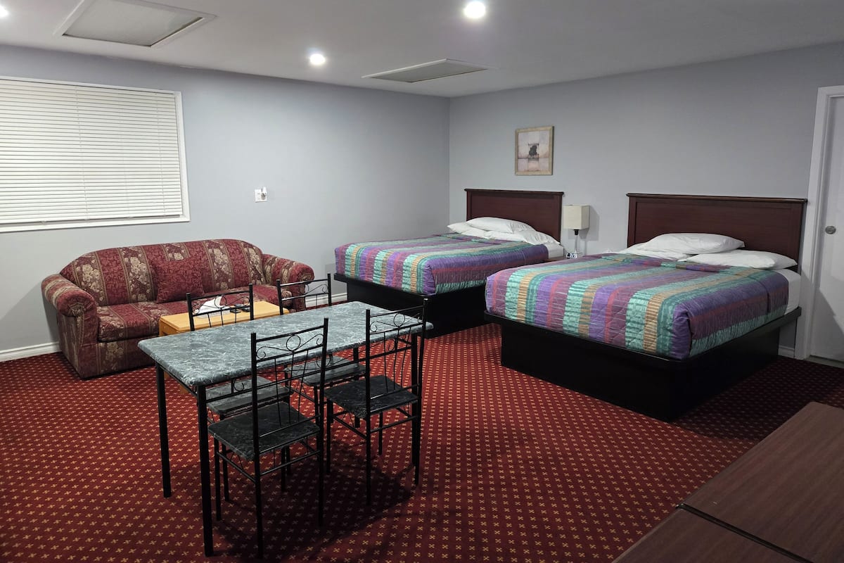 Ein Hotelzimmer mit zwei Betten, einem Schlafsofa, einem Tisch und einem Stuhl.