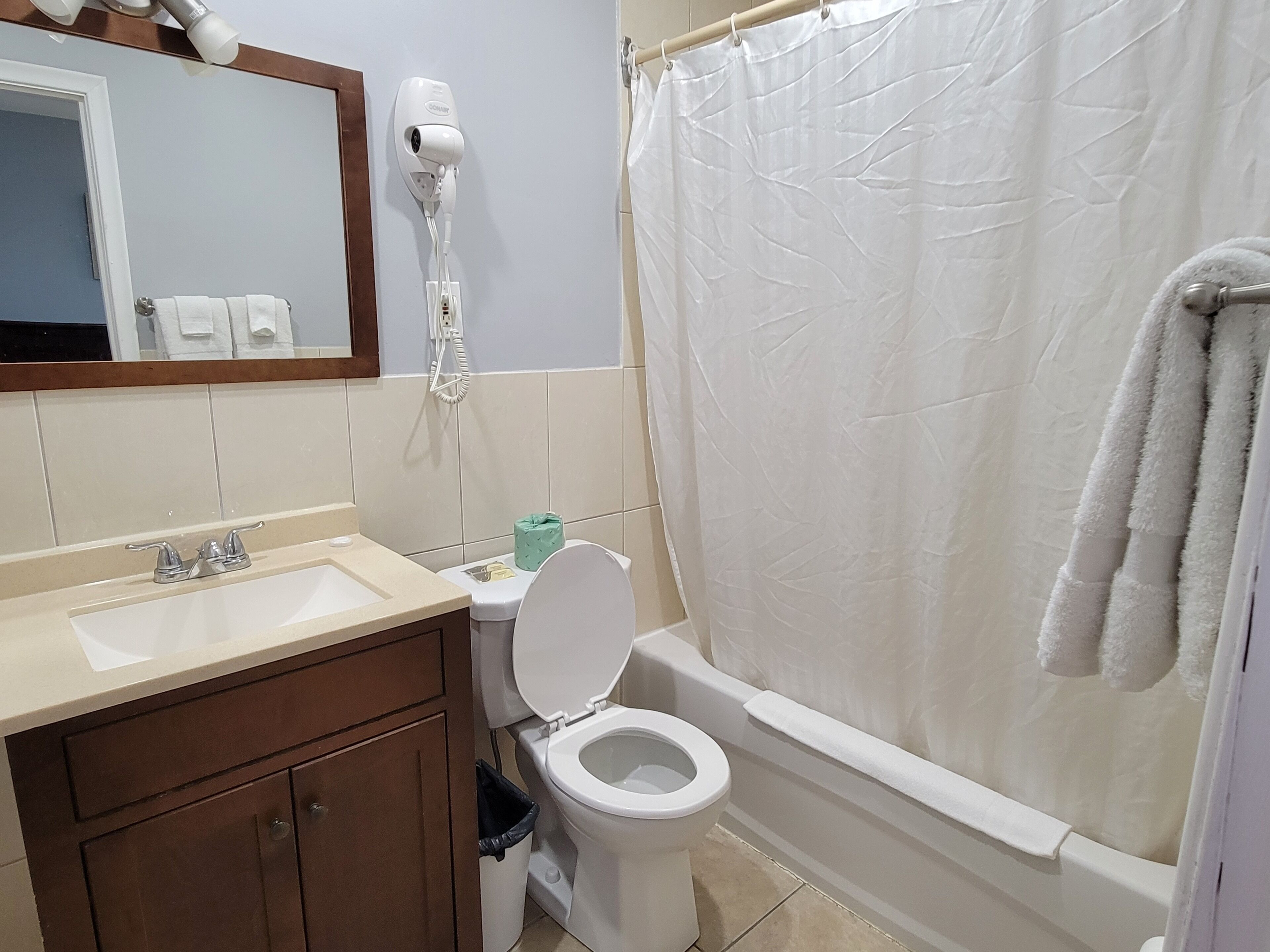 A bathroom with a sink, toilet, and a hairdryer mounted on the wall.