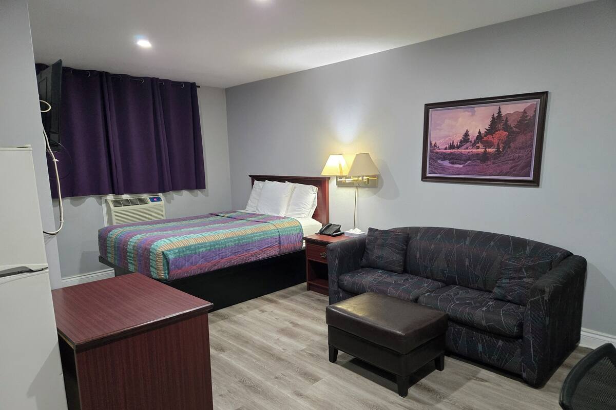 Ein Hotelzimmer mit Bett, Sofa, Schreibtisch und Lampe.