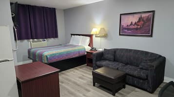 Una habitación de hotel con una cama, un sofá, un escritorio y una lámpara.