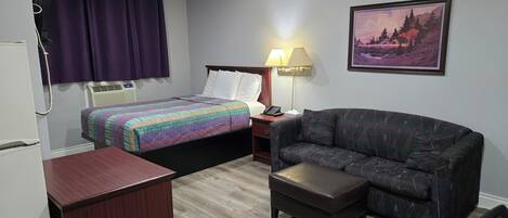 Una habitación de hotel con una cama, un sofá, un escritorio y una lámpara.
