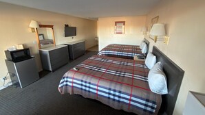 A hotel room with two beds, a desk, a microwave, a refrigerator, and a TV. - Regal Motel in Las Vegas, New Mexico (Las Vegas)