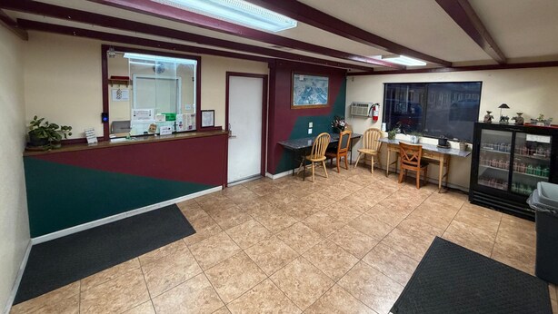 A reception area with a counter, chairs, a small table, and a display cabinet. - Regal Motel in Las Vegas, New Mexico (Las Vegas)