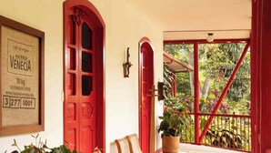 Una puerta roja, un letrero enmarcado y una planta en maceta.