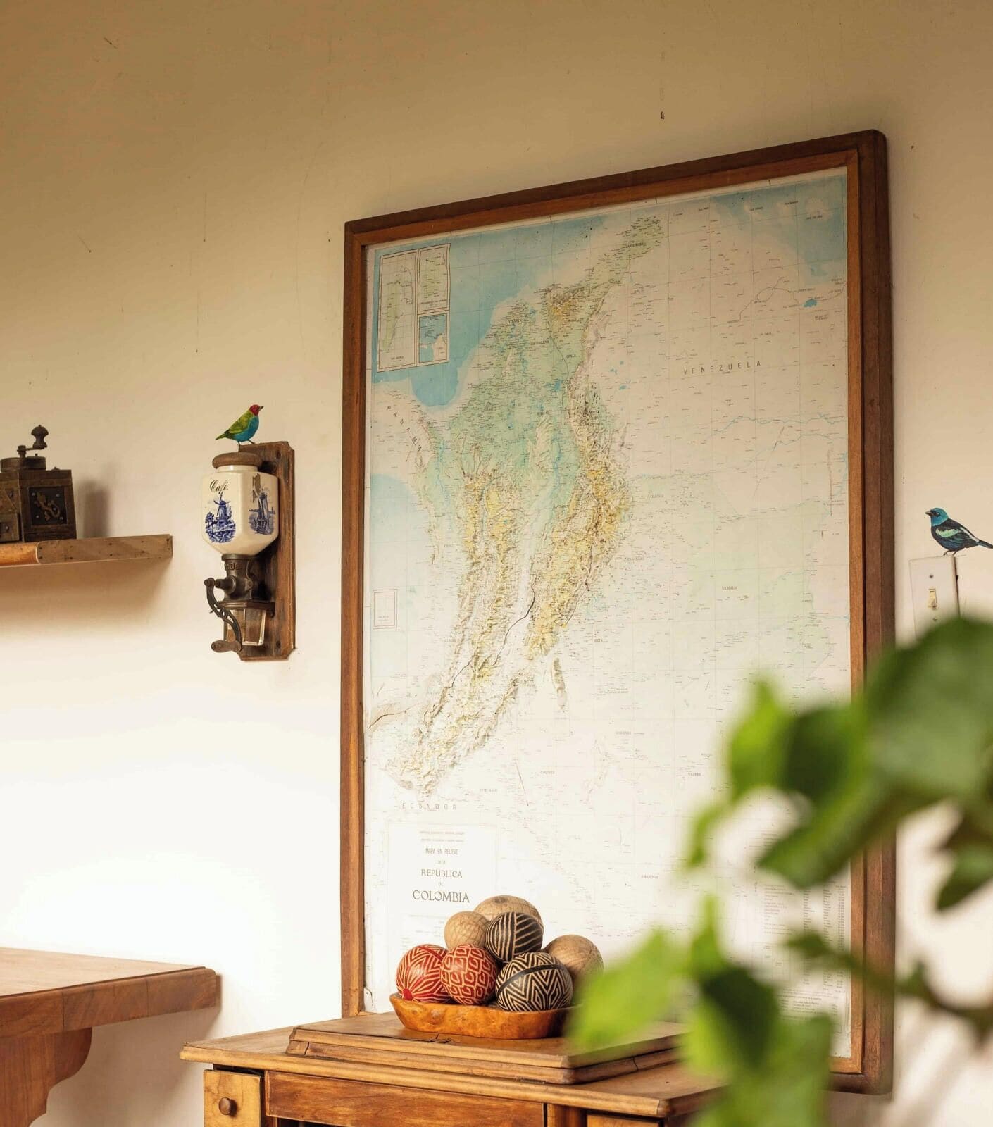 Un mapa colgado en la pared, una mesa de madera con objetos decorativos y una figurita de pájaro.