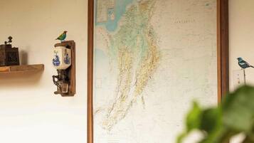 Un mapa colgado en la pared, una mesa de madera con objetos decorativos y una figurita de pájaro.