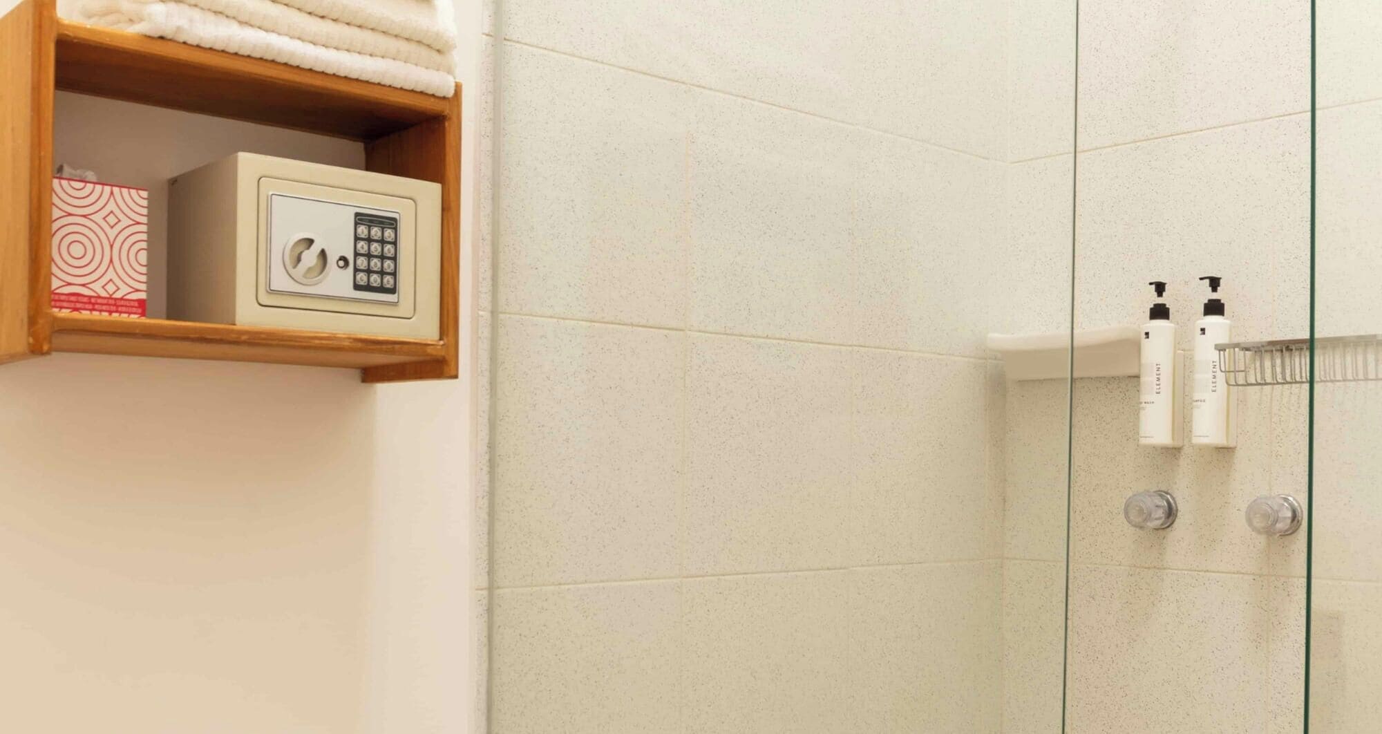 Een badkamer met een douche, een plank met toiletartikelen en een doos.