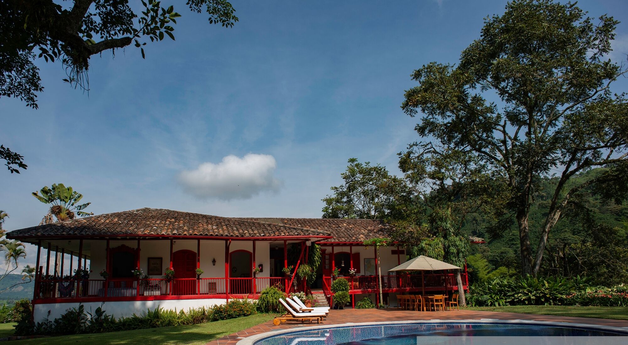 Une villa avec piscine, des balustrades rouges et un jardin.