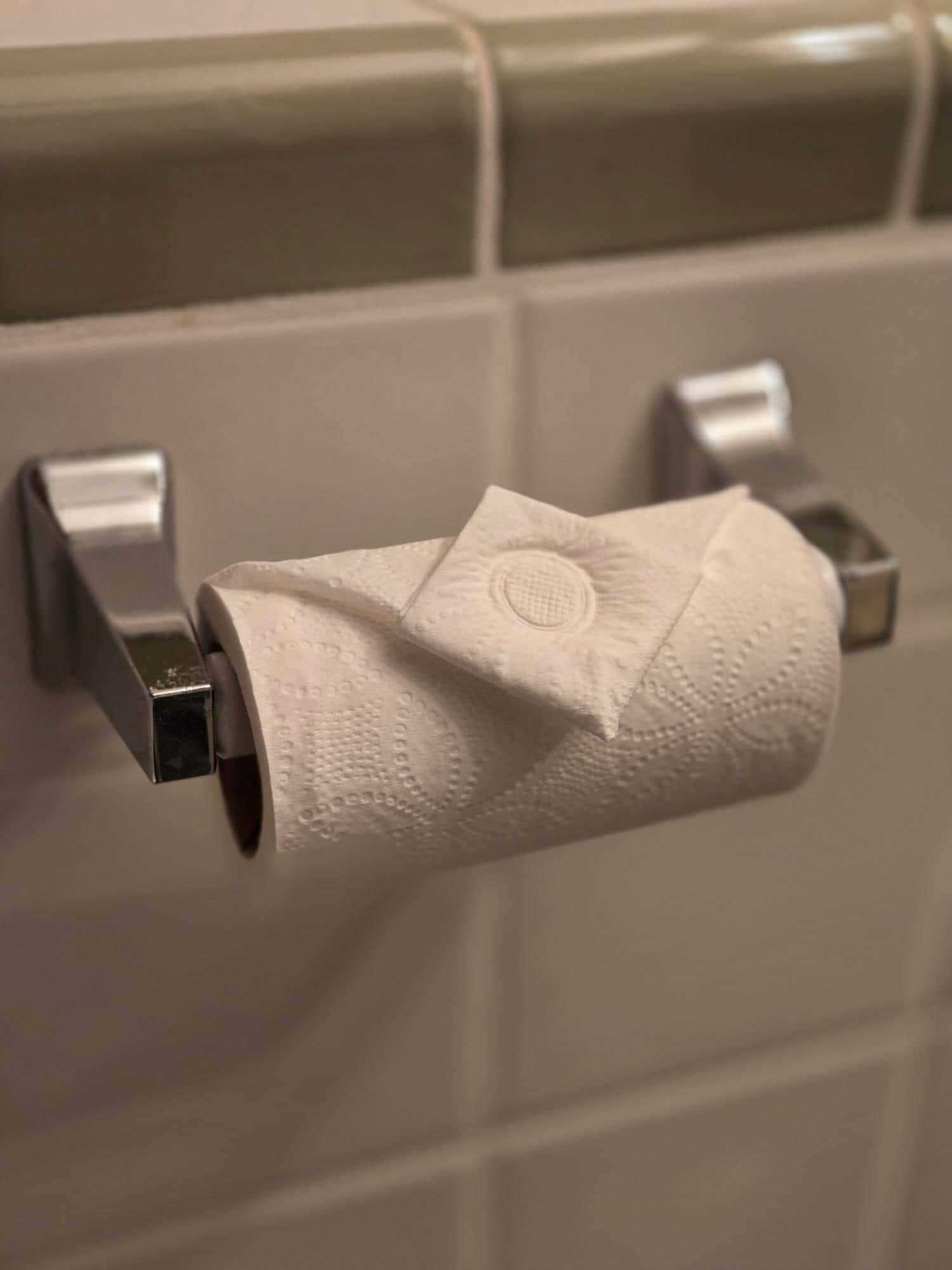 Un rollo de papel higiénico sujeto a un dispensador instalado en la pared de un baño.