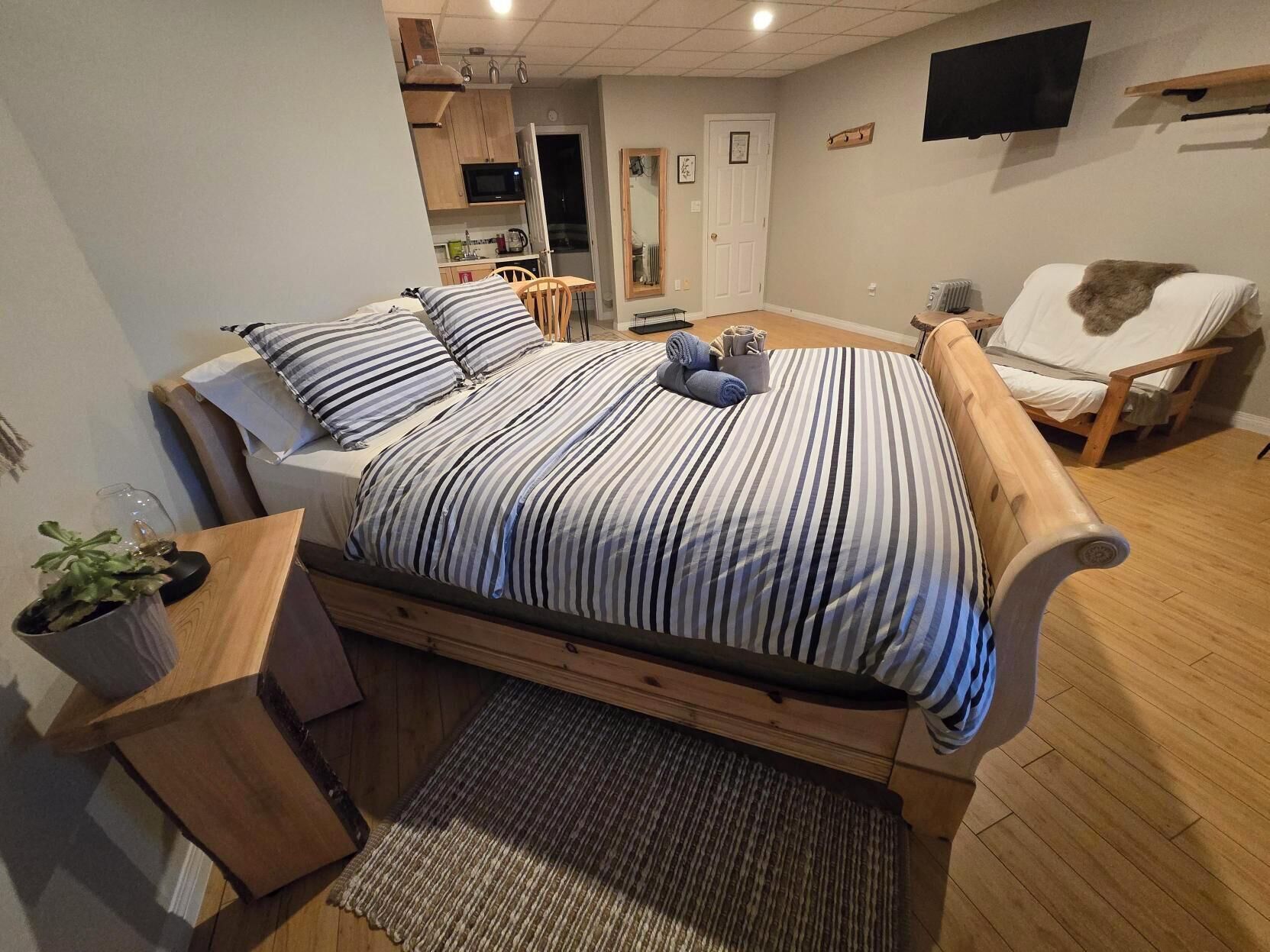 Un dormitorio con cama, una silla, una mesita y un televisor.