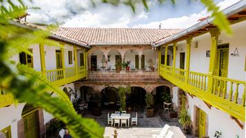 A courtyard with a tiled roof, yellow railings, and potted plants.