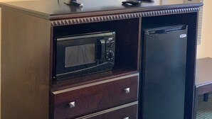 A dark wooden cabinet with a flat-screen TV, a microwave, and a small refrigerator. - Blackwater Inn (Milton)