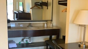 A hotel bathroom with a dark wood vanity, a mirror, a sink, and a chair. - Blackwater Inn (Milton)