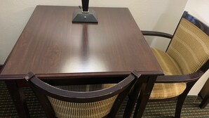 A square wooden table with a black base, surrounded by two dark wooden chairs with woven seats. - Blackwater Inn (Milton)