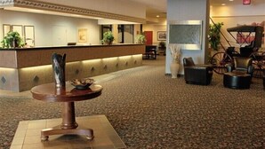 A lobby with a reception desk, a round table with a sculpture, and a seating area with chairs and a sofa. - Westlock Inn and Conference Centre (Westlock)