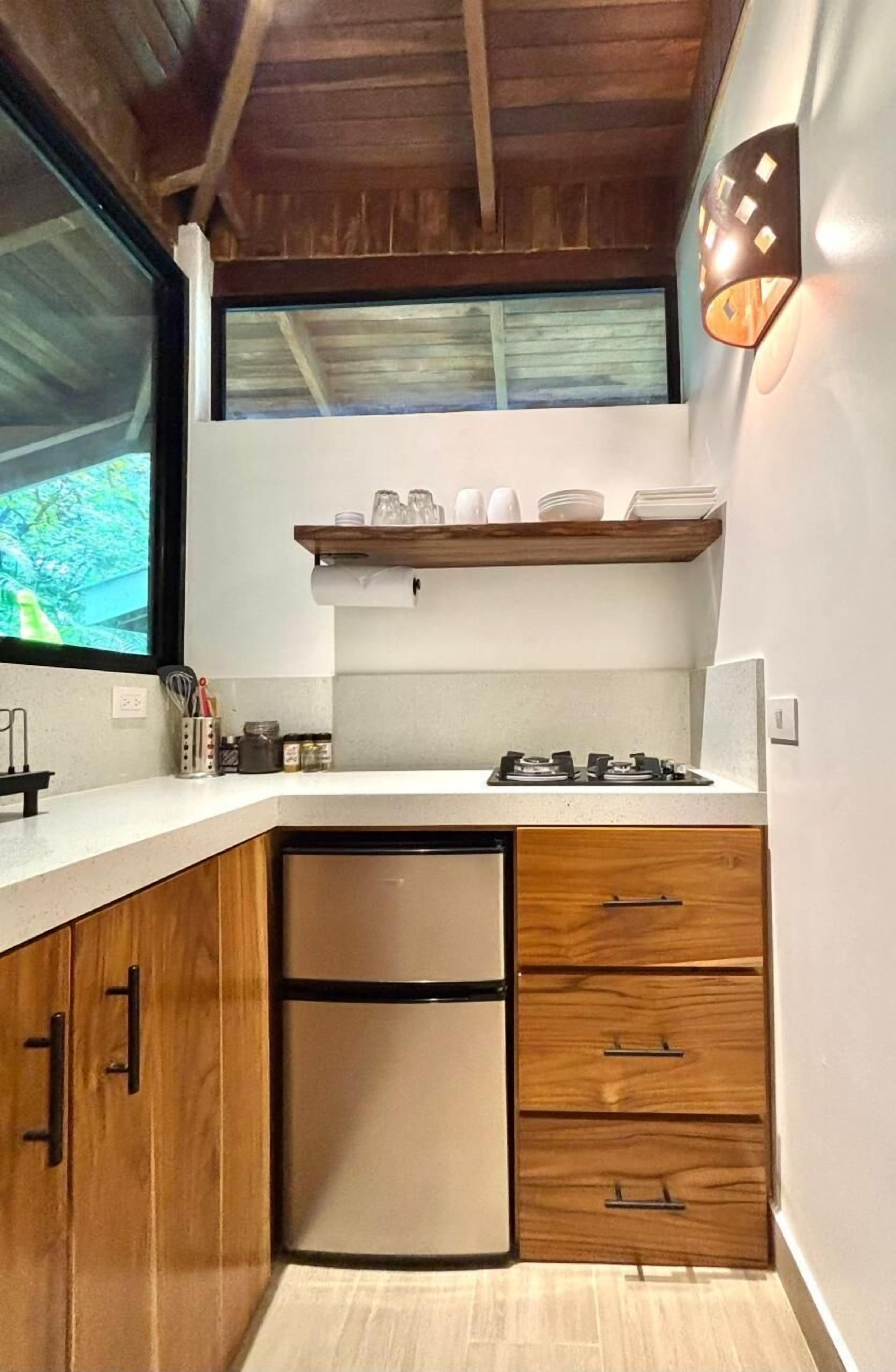 A compact kitchen with wooden cabinets, a built-in dishwasher, and a small window above the sink.