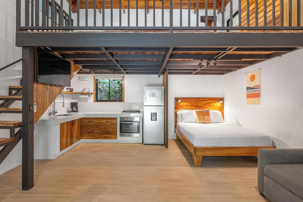 Ein kleines Apartment mit Küchenzeile, einem Bett und einer Treppe.