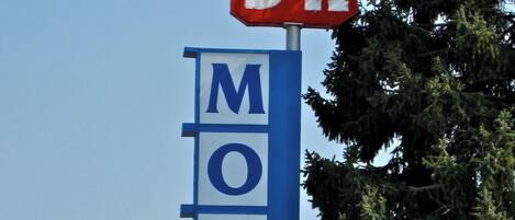 A motel sign with 'D.K' and 'MOTEL' on it, a 'CABLE - Wi-Fi' sign, and a 'WELCOME TO OUR PLACE LUNDROMAT' sign.