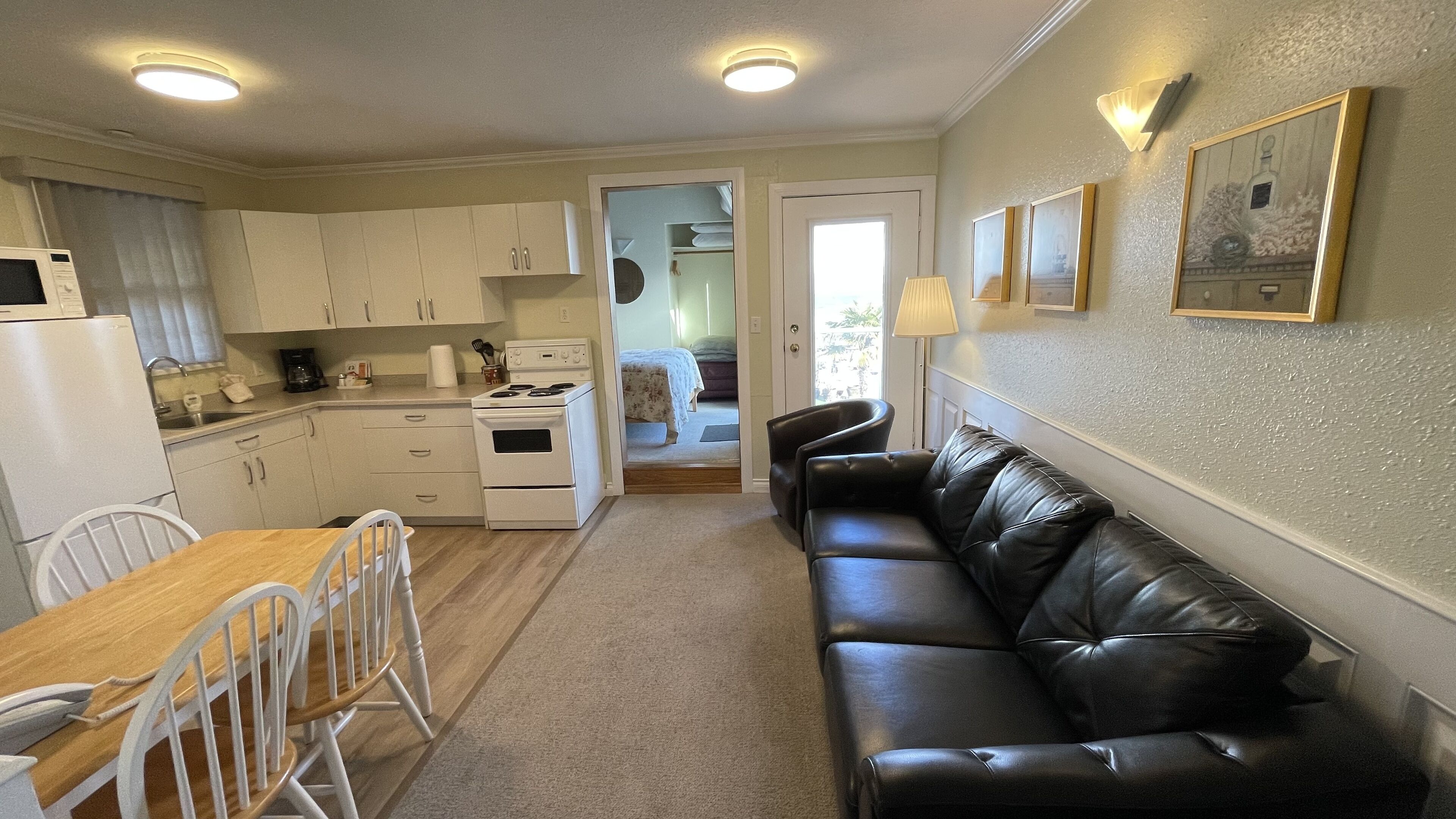 A compact kitchen with white cabinets, a stove, and a dining area with a table and chairs.