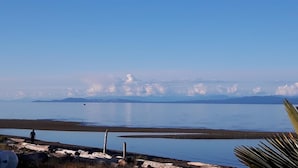 Um lago calmo com céu claro e montanhas ao longe.