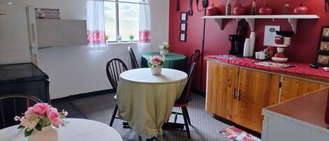 A cozy dining area with a round table, chairs, and a cabinet with a red countertop.