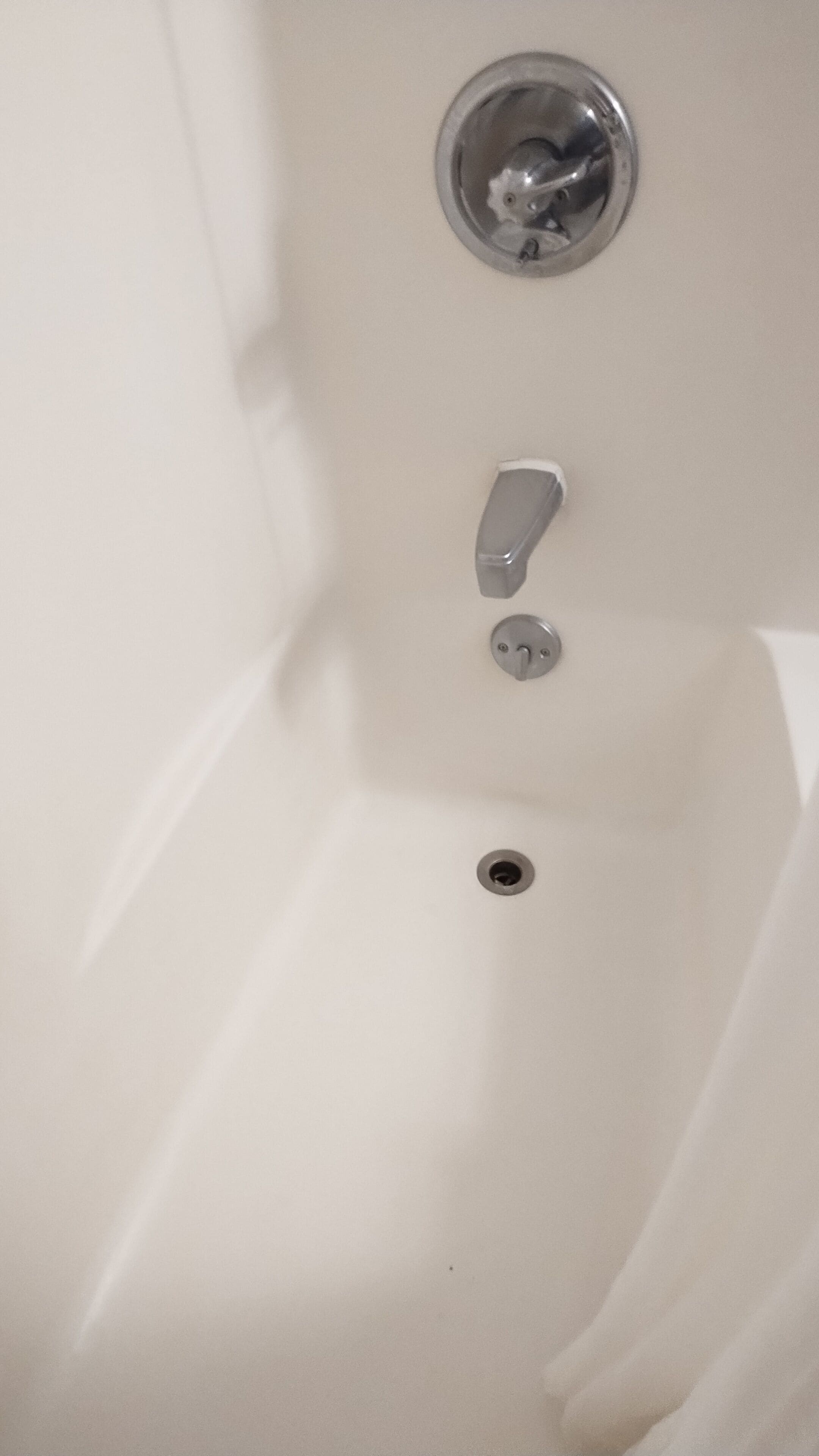 Una bañera blanca con grifo cromado, un solo mando y desagüe.