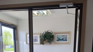 A room with a carpeted floor, a door leading outside, and two framed pictures on the wall. - Northgate Inn Motel (Challis)