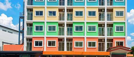 Un edificio de varios pisos con fachada plana, balcones y entrada a nivel de calle con porche cubierto.