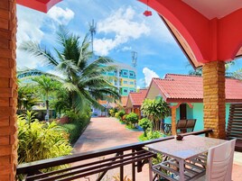 A balcony with a view of a pathway lined with palm trees and buildings.