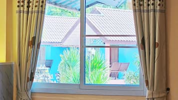 Una ventana con vista a un edificio azul y plantas verdes al exterior.