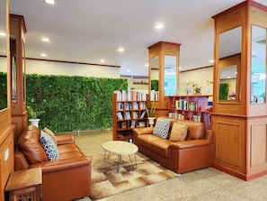 Uma área de estar acolhedora com sofás de couro, uma mesa de centro e uma estante repleta de livros.
