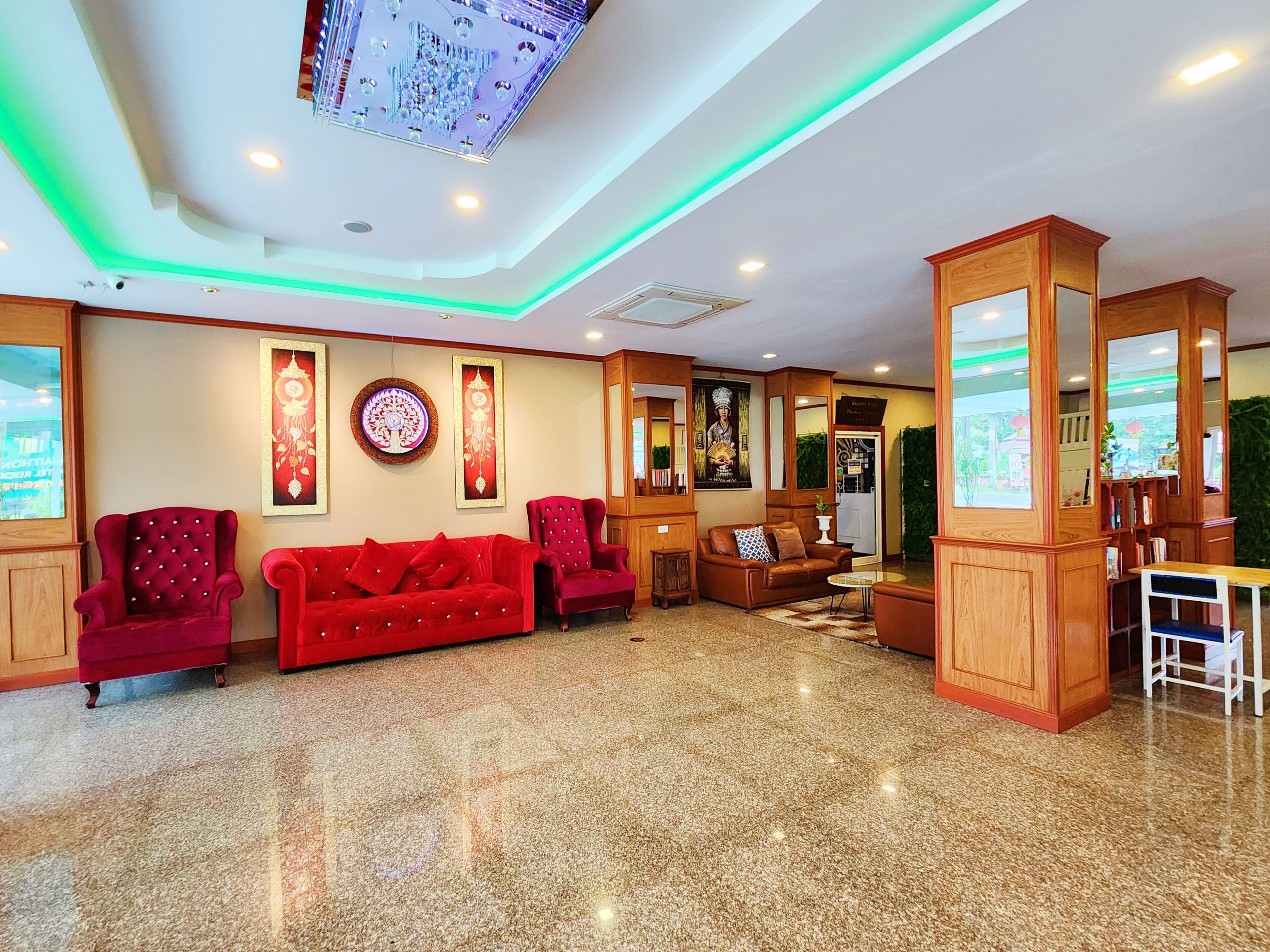 A hotel lobby with a red sofa set, wooden furniture, and a digital screen on the ceiling.