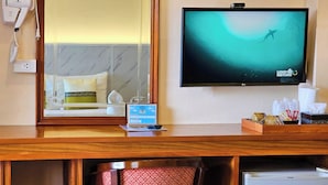 A hotel room with a bed, a TV displaying a nature scene, a hairdryer, a Wi-Fi sign, and a small refrigerator. - Phaithong Sotel Resort (Chalong)