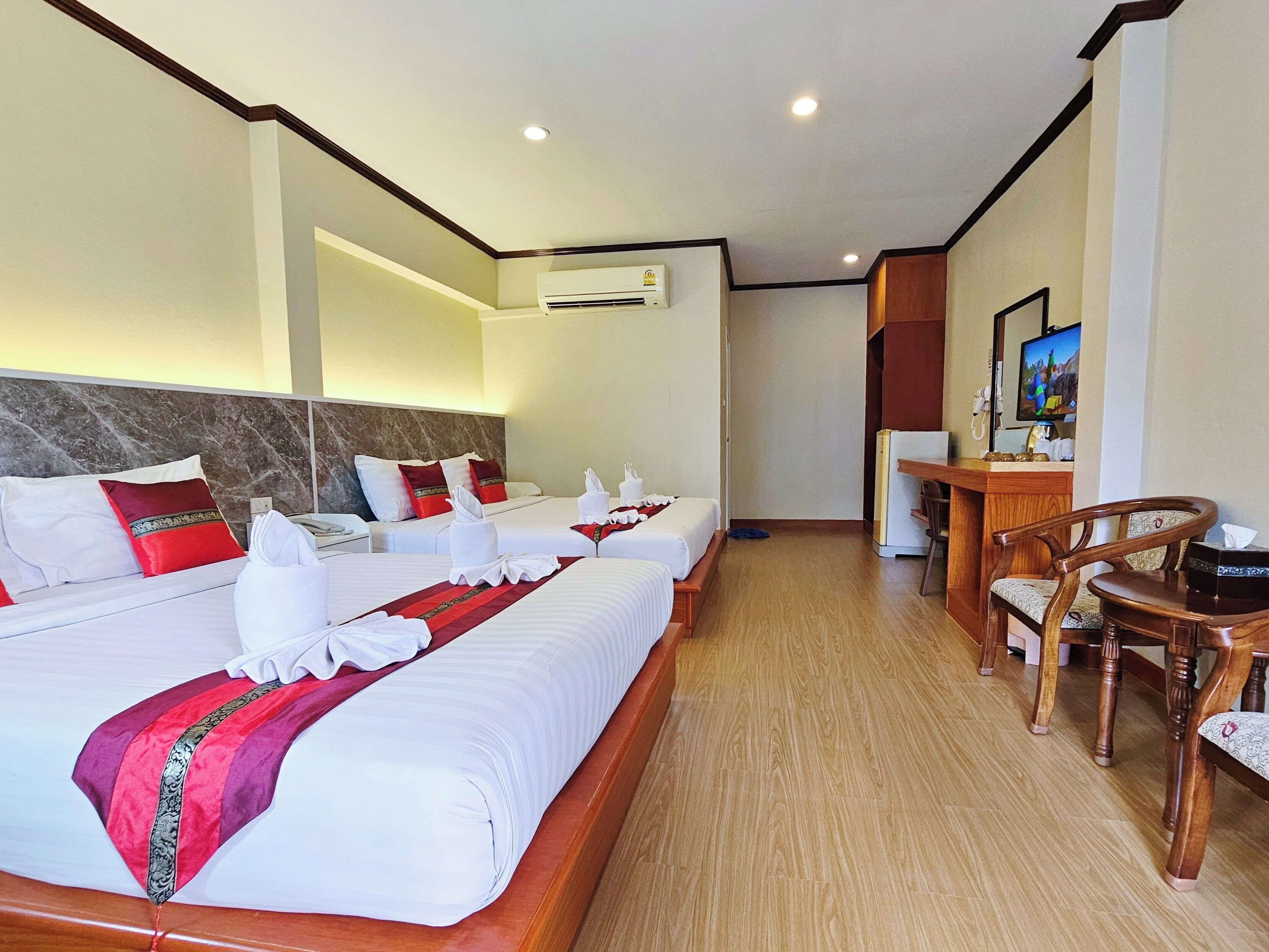 Una habitación de hotel con dos camas, un escritorio, una silla, un equipo de aire acondicionado y un televisor.