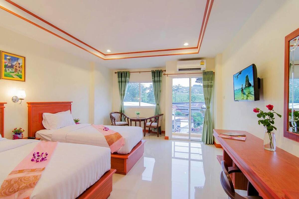 Una habitación de hotel con dos camas, un escritorio de madera, televisión y balcón con vistas.