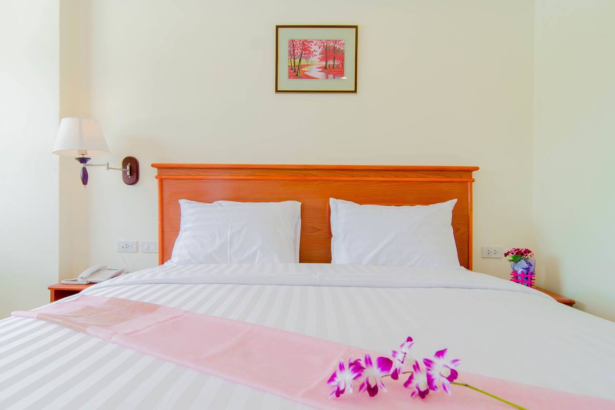 Una cama bien hecha con sábanas blancas, cabecera de madera y un corredor decorativo rosa.