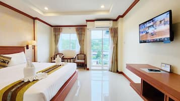 Habitación de hotel con una cama grande, televisión, escritorio y vista al exterior.