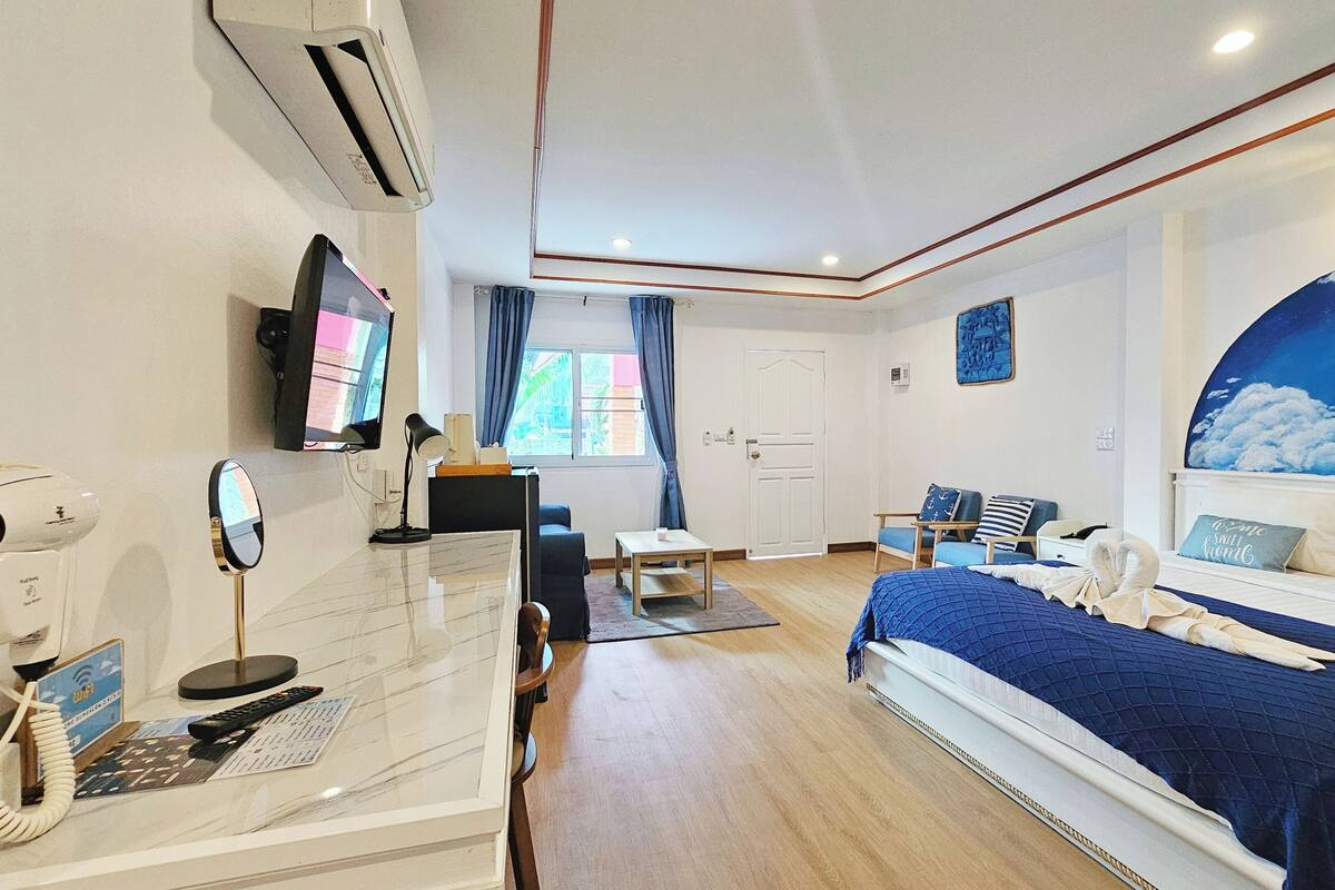 Una habitación de hotel con una cama, un escritorio con computadora, un televisor y una ventana con cortinas.