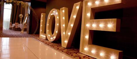 Een groot, verlicht 'LOVE'-bord in een hotellobby met een kamerbreed tapijt en een decoratieve boog.