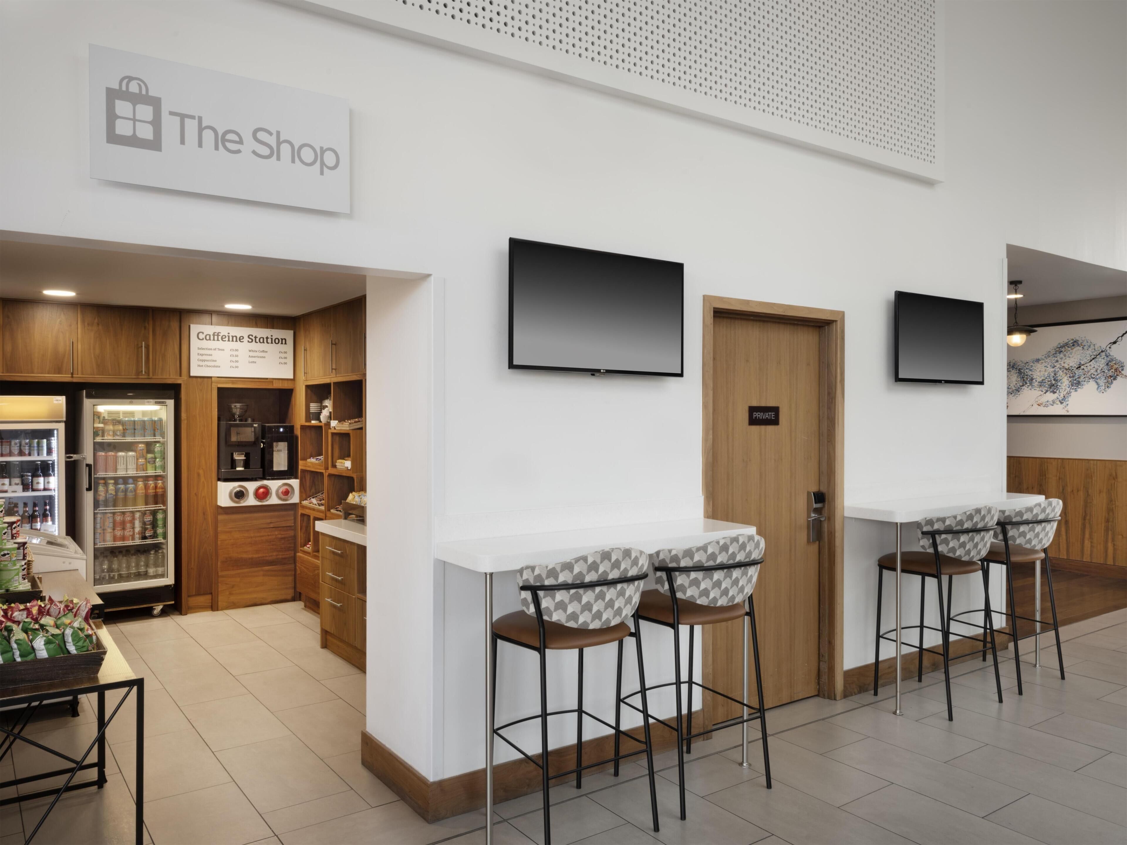 Un café moderno con una estación de café, taburetes y un espacio privado.