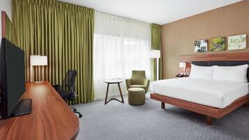 Habitación de hotel con una cama grande, un escritorio con computadora, una silla y una mesita.