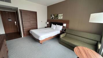 Ein Hotelzimmer mit Bett, Sofa, kleinem Tisch und einer Tür.