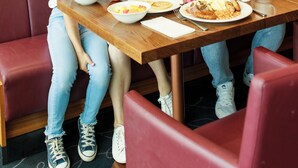 A family dining at a restaurant with a wooden table, red cushioned seating, and a tiled backsplash. - Hilton Garden Inn Sunderland (Sunderland)