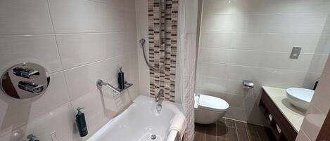 Une salle de bain moderne équipée d’une baignoire, d’une douche et de toilettes.