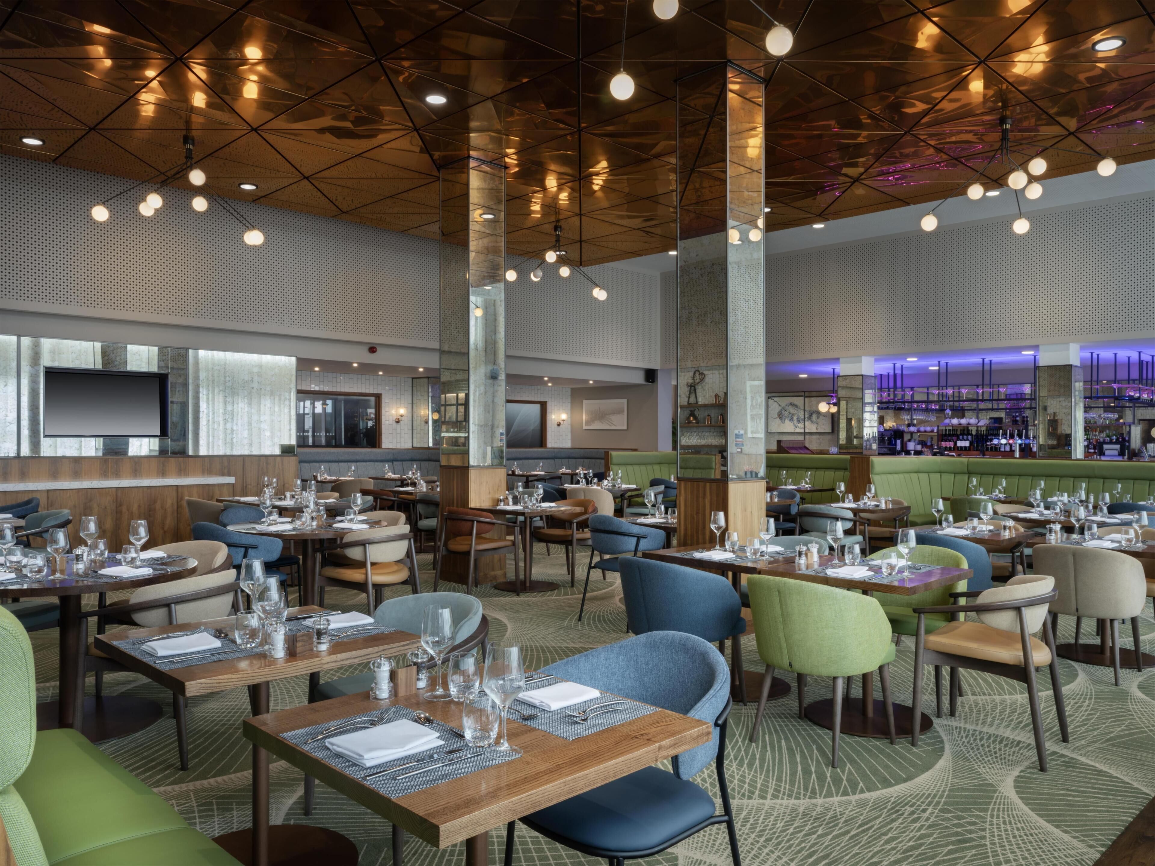 Un interior de restaurante moderno con varias mesas, sillas y una zona de bar.
